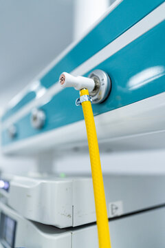 Vertical Shot of CO2 Gas Connector in Hospital Wall. Vertical close-up of a carbon dioxide gas connector plugged into a medical wall panel with a yellow tube used for insufflation during surgery.