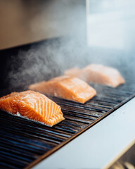 Salmon fillets grilling on barbecue with smoky steam