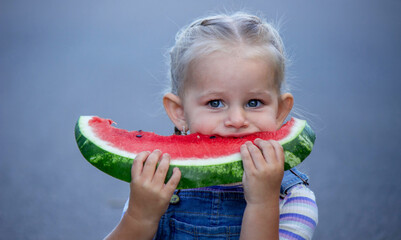 Happy little girl eating a piece of juicy watermelon.
