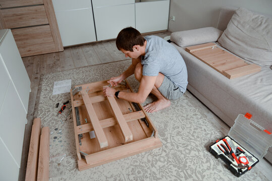 Man assembling flatpack furniture at home. DIY project. Interior.