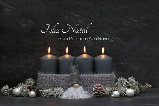 Cart&atilde;o de Natal: Sauda&ccedil;&otilde;es natalinas em portugu&ecirc;s com velas cinzentas acesas, enfeites de Natal, ramos de pinheiro e um gnomo. Feliz Natal e um pr&oacute;spero Ano Novo.