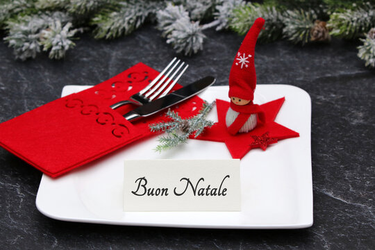 	Decora&ccedil;&atilde;o de mesa natalina com pratos, talheres e enfeites festivos; um marcador de lugar diz "Feliz Natal".