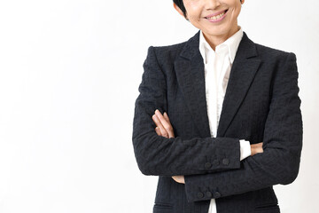 スーツ姿で腕組みをする笑顔の中高年のアジア人女性