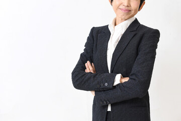 スーツ姿で腕組みをする笑顔の中高年のアジア人女性