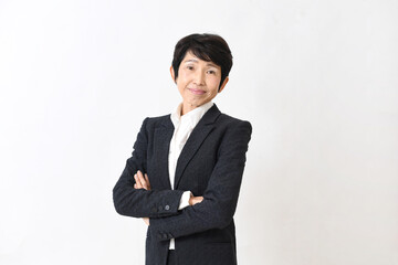 スーツ姿で腕組みをする笑顔の中高年のアジア人女性