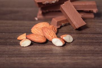 Almonds and chocolate rest on a wooden floor, creating a warm and natural food-themed still-life scene.