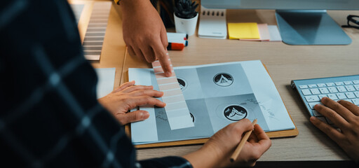 A detailed view of a collaborative design session in a modern office. Hands engage with sketches and color palettes, illustrating creativity and teamwork in a workspace. SACTR