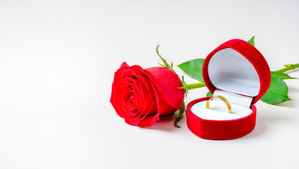 Romantic moment captured with a red rose and golden ring in a velvet box, symbolizing love and commitment