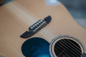 Fototapeta premium Close-up of an acoustic guitar showing the bridge, strings, and round sound hole in natural light.