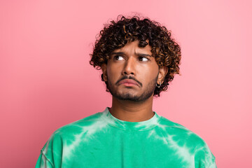 Obraz premium Young man with curly hair wears green tie dye jumper looking puzzled against pink background