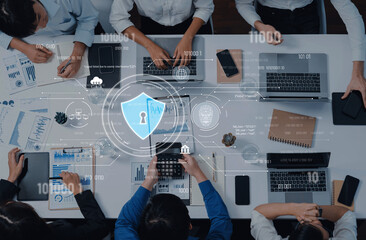 A dynamic scene of a team collaborating in a modern office, surrounded by laptops and security graphics, emphasizing data analysis and digital safety in business. Trope