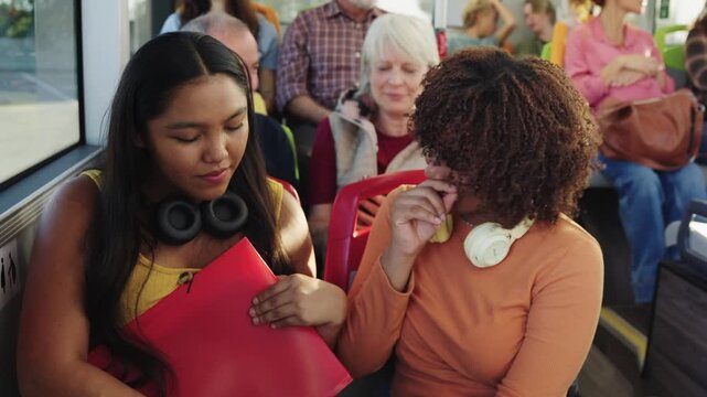 Two young female students talking on a crowded bus