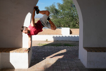 Man performing handstand balancing calisthenics outdoors under archway