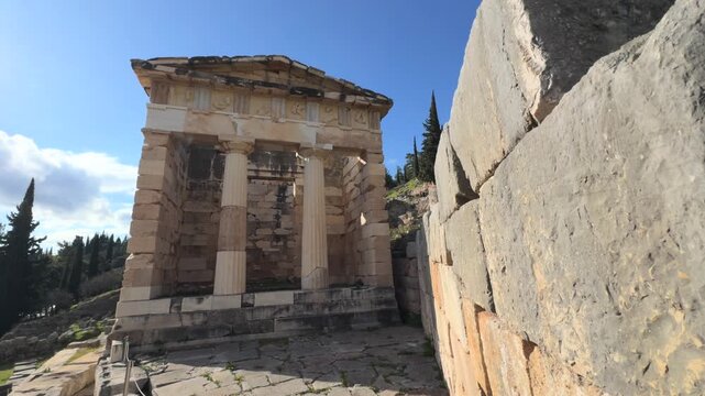 Delphi temple 4k video. Panoramic view of the ancient Greek theater of Delphi built into the rocky mountainside, overlooking a deep green valley under a clear blue sky.