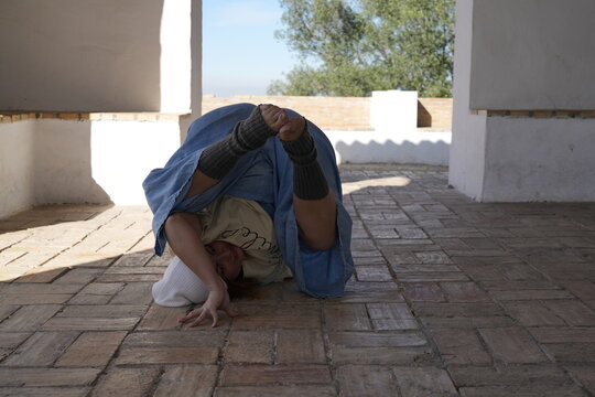 Woman performing acrobatic yoga pose in outdoor patio