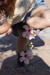 Woman practicing yoga outdoors with hibiscus flowers