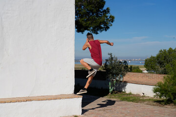 Man performing outdoor fitness training jumping on wall