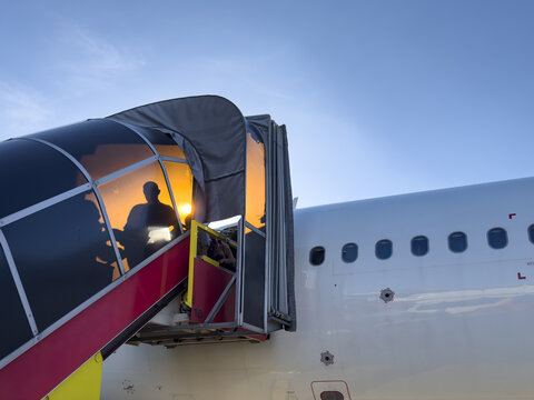 View of boarding stairs with red accents leading into the bright interior of a plane against a blue sky, Hanoi, Hanoi, Vietnam.