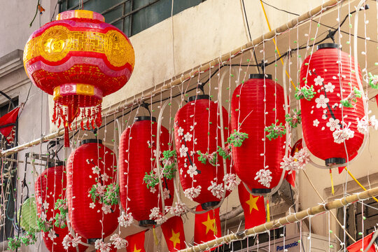 View of vibrant red lanterns adorned with delicate white blossoms and strung with twinkling lights, a celebration of culture and color, Hanoi, Hanoi, Vietnam.