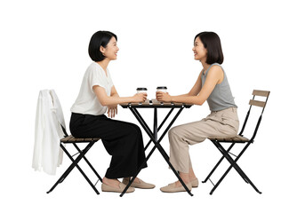 Two women having coffee in casual conversation at small outdoor table in soft natural lighting for social media isolated on white background