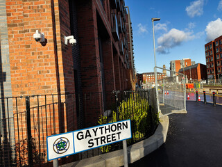 Gaythorn Street in Manchester housing development with brick buildings, security cameras and construction fencing outside