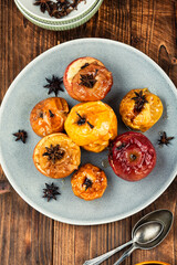 Baked apples with spices on wooden surface.