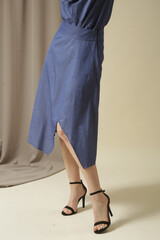 Female model wearing monochrome denim blue outfit. Midi skirt and bow-tie neck blouse. Fashion studio shot.