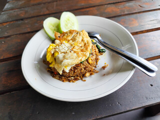Fried rice with egg and vegetables in a white plate, at an outdoor stall during the day.