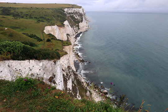 Landscape photo of the Dover chalk cliffs and the English Channel coastline against a stormy sky near Dover, United Kingdom