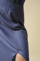 Female model wearing monochrome denim blue outfit. Midi skirt and bow-tie neck blouse. Fashion studio shot.