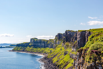 Isle of Skye,  Kilt Rock - stunning coastal cliffs overlooking turquoise sea with lush green hillsides and blue sky
