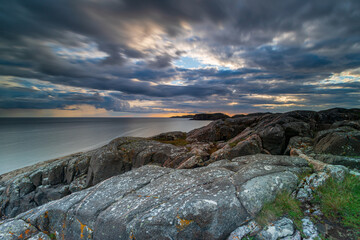 Oldshoremore beach - dramatic rocky coastline at sunset with cloudy sky over calm ocean