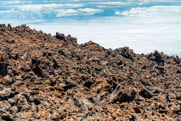 Obraz premium Rugged lava rocks meet blue sky and white clouds in a desolate coastal landscape