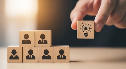 Hand placing wooden cube with lightbulb icon on stacked cubes with people icons