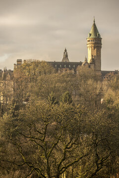 View of golden light washes over the iconic tower, nestled amongst bare winter trees, creating a serene scene of Luxembourg's architectural beauty, Luxembourg City, Luxembourg.