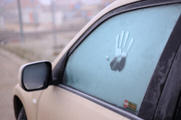 Handprint on a frozen car window during a frosty day