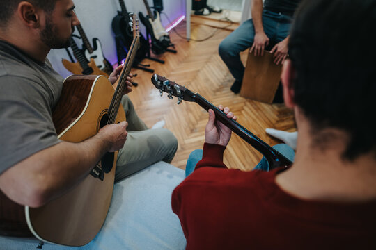 Two guitar players in a cozy home room share a casual jam session with acoustic guitars. A relaxed, musical moment in a comfortable living space.