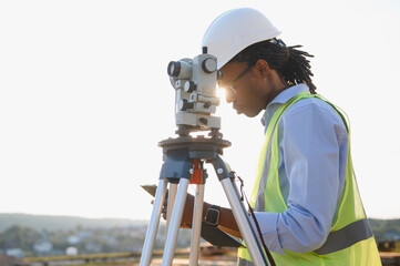 African american surveyor working with professional surveying equipment