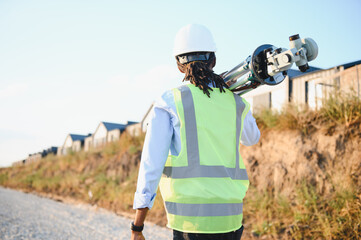 Surveyor carrying equipment walking at new development site