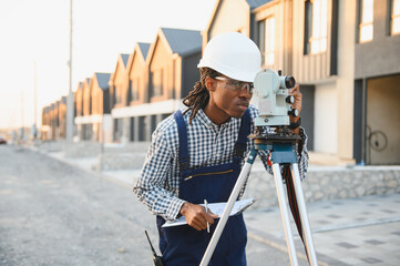 African american surveyor using theodolite for land measurement