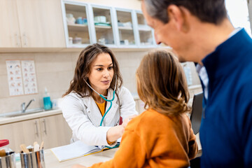 Fototapeta premium Female pediatrician consulting with a father of young child during a medical checkup in clinic.
