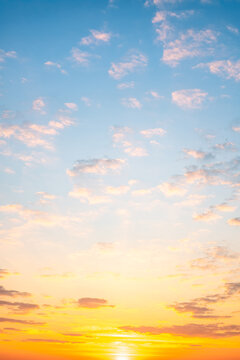 Sunset or sunrise sky with a vibrant gradient of orange, gold, and soft blue. Clear atmosphere with wispy clouds. Peaceful, natural light background. hope, freedom, new day Concepts, Vertical