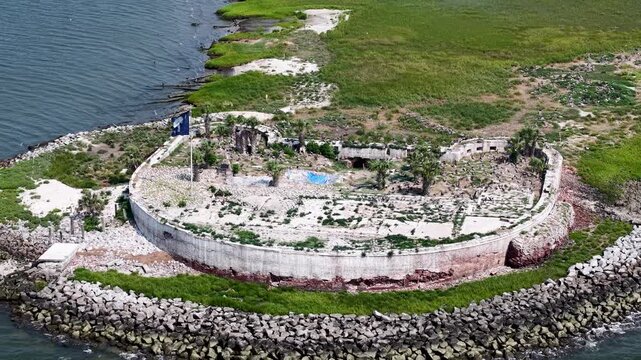 Overhead drone view of Castle Pinckney showing the full circular fort structure, rubble interior, and surrounding riprap seawall on a grassy island