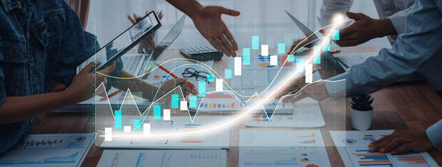 Professionals engage in a strategic meeting while analyzing data charts and digital graphs. A dynamic office setting showcases teamwork and collaborative efforts. Axiom