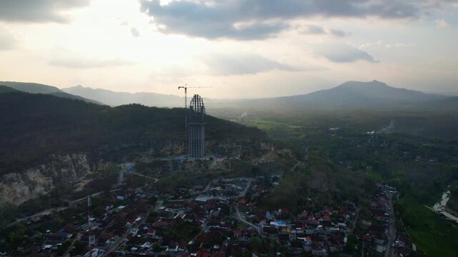 Aerial drone footage of the Reog monument in Ponorogo, Indonesia, still in construction process, with the sunset behind