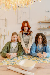Three friends gather in a cozy studio, focusing on their pottery skills. The warm ambiance and...