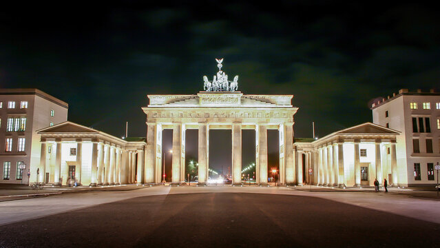 Brandenburg Gate at night, Berlin, Germany. The illuminated neoclassical monument standing under a dark sky with golden lighting.