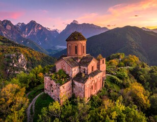 Ancient stone building stands on a hilltop. Green trees and winding paths surround it. Majestic mountains are in the distance