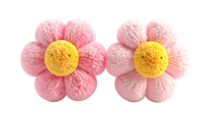 Two fluffy, flower-shaped pillows in soft pink with yellow centers and stitched faces. They resemble cheerful daisies