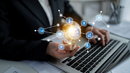 A business professional engages with advanced digital technology, showcasing various icons and symbols while working on a laptop in a modern office setting. Tessel